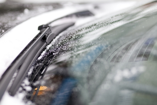 A view of a windshield on a car that is covered in snow and water.