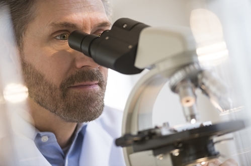 A doctor or researcher looking through a microscope to a coating.