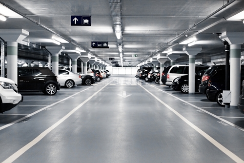 A large and expansive underground garage is filled with many vehicles.