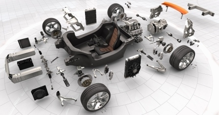 A picture of a car that has been completely disassembled in a white room.