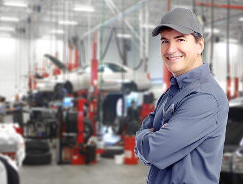 An employee in a Mexican factory proudly stands at the forefront of an automobile manufacturing facility.
