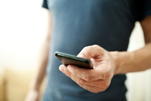 There is a man holding an electonic item in the form of a cell phone.