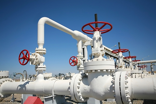 There is a picture of large steel white pipelines that help transport natural gas as an energy source.