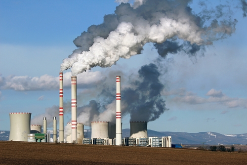 A picture of the exterior of a manufacturing facility in Mexico that is surrounded by a mountain range and smoke.