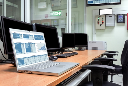 A large table with multiple computers on it but only one powered on laptop.