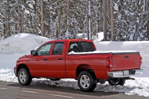 A large red truck in a forest covered with snow.