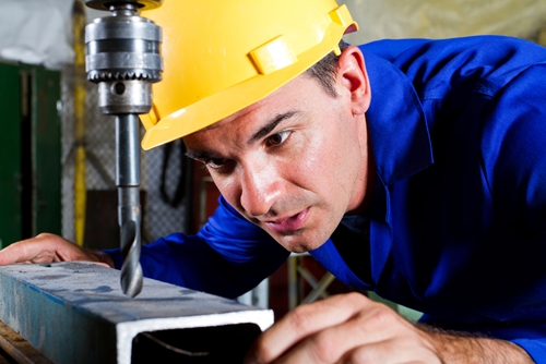 There is an emplyee working to cut a cold hard piece of steel.