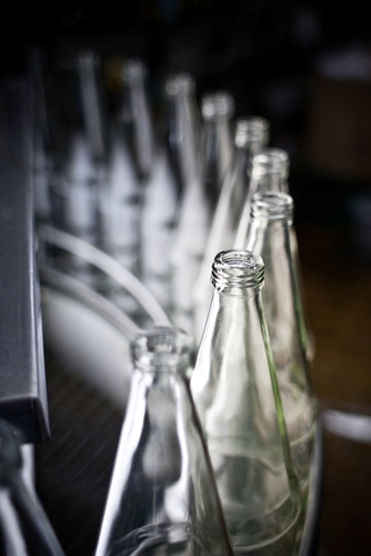 A line of glass bottles that have been manufactured in a manufacturing facility in Mexico.