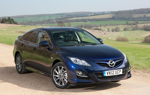 A blue new blue Mazda vehicle stands in the middle of the Mexican landscape.
