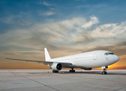 There is a pacture of a plane still grounded with a beautiful sunset in the background.