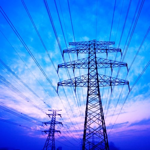 There are two big power towers along with a beautiful sunset in the background.