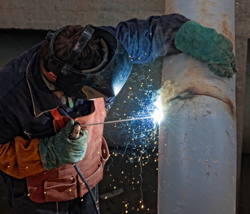 A man working to cut out a large metal circle with advanced welding equipment.