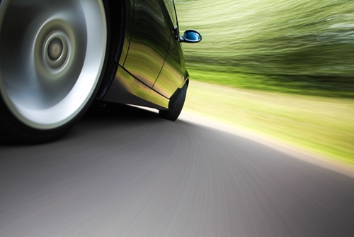 A view of the bottom of car speeding through a highway in the middle of a forest.