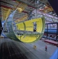 There is a picture of the inside of a manufacturing facility where there is the shell of a new airplane being built.