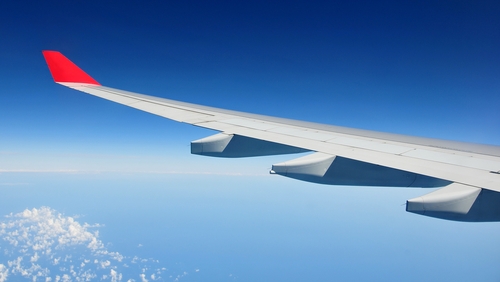 A picture of the wing of a plane flying in the clear blue skies.