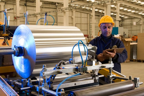 A factory employee working with a large roll of a metal in a manufacturing facility in Mexico.
