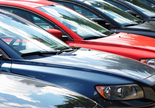 A view at several different colored cars parked next to each other in a row.