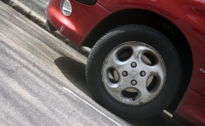 The focus of the picture is on the front left tire of a red automobile.