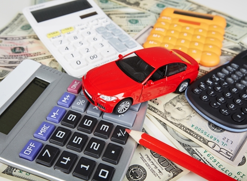 A view at a toy car driving across for different multicolored calculators.